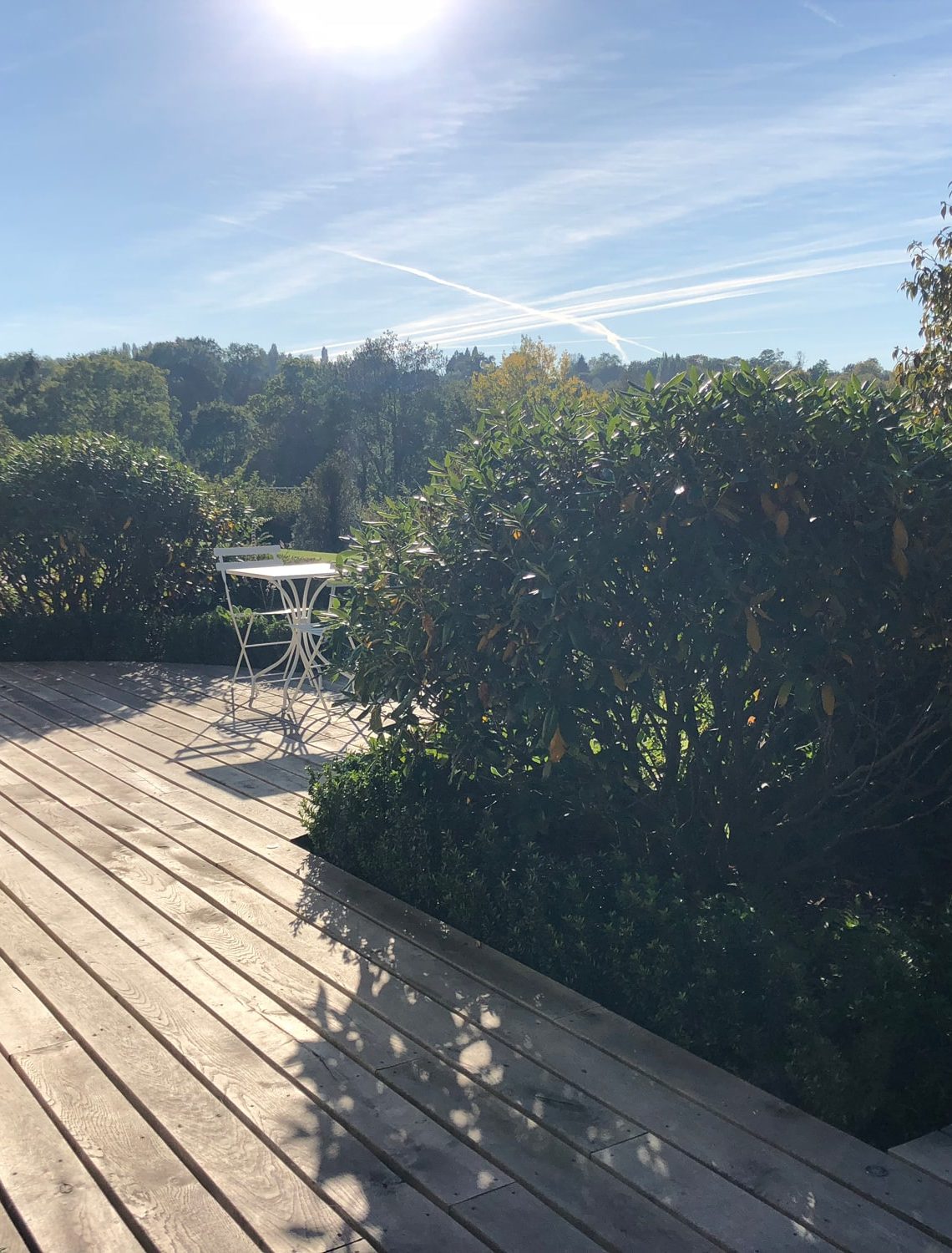 Terrasse avec vue sur le vallon forestier dans le jardin à l'horizon